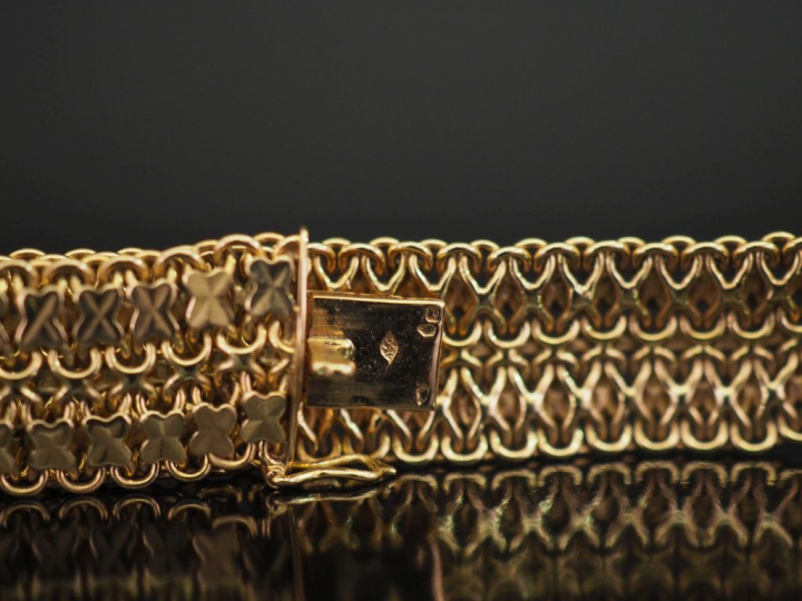 	Bracelet souple en or jaune 750, à décor de croisillons. Larg. 1,7 cm
