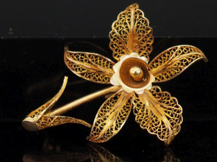 Broche en or jaune 750 en forme de fleur, à décor ajouré et filigrané.