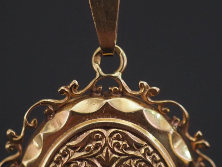 Pendentif ovale en or jaune 750, à décor de rinceaux feuillagés.  Joli
