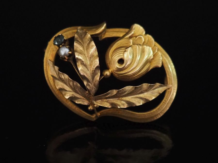 Broche ovale ajourée en or jaune 750, à décor d'une fleur et agrémenté