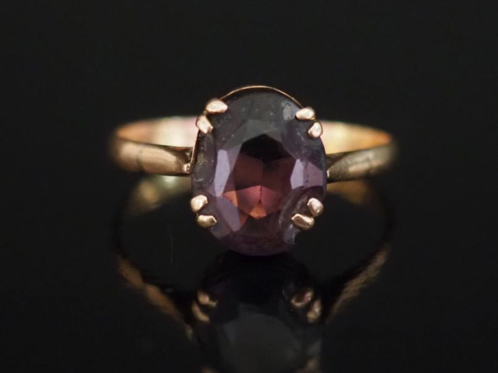 Bague en or jaune 750, sertie en son centre d'une pierre violette.  TD