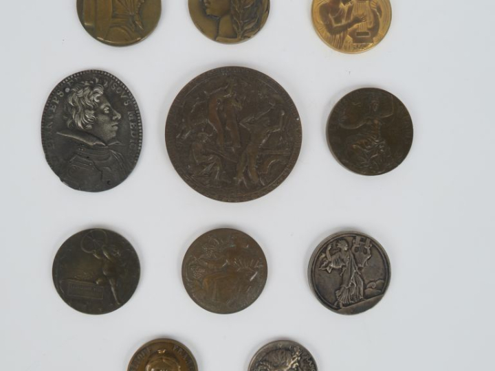 11 différentes médailles en bronze patiné, argenté ou doré.  Signées :