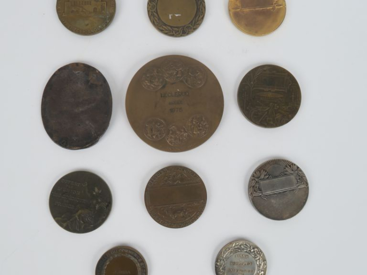 11 différentes médailles en bronze patiné, argenté ou doré.  Signées :