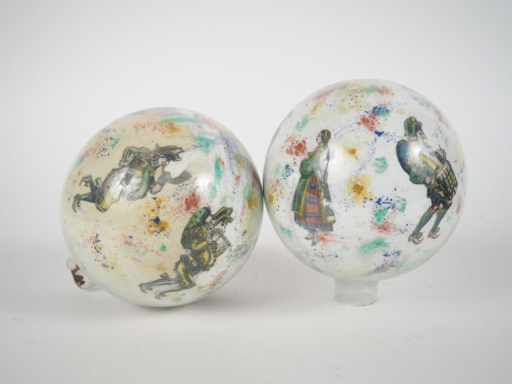 2 boules porte-perruque en verre églomisé à décor de personnages. H. 1