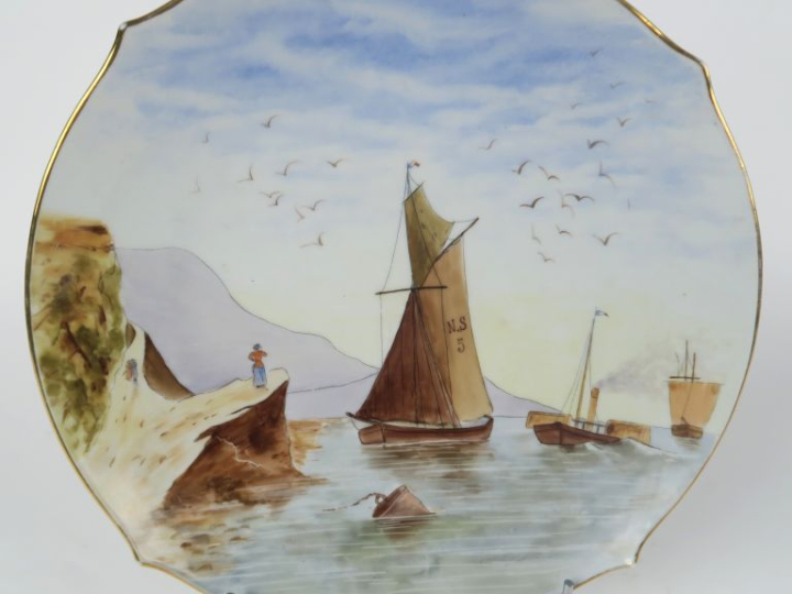 Plat en porcelaine à décor peint à décor d'une marine. Diam. 33,5 cm.