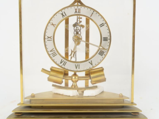 Vente aux enchères ATO. Pendule en laiton et plexiglas, cadran à chiffres romains. Signée