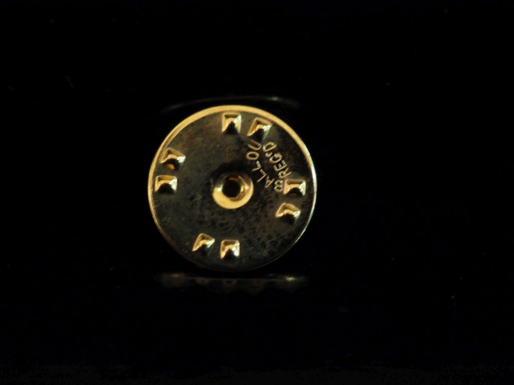 YVES SAINT LAURENT Pin's en métal doré figurant le monogramme de la ma