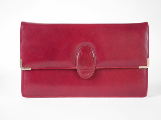 Vente aux enchères CARTIER Grande pochette en cuir bordeaux.  Fermeture à rabat et pressi