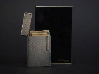Vente aux enchères DUPONT Briquet eun métal argenté, à décor guilloché.  H. 5,8 cm Signé.
