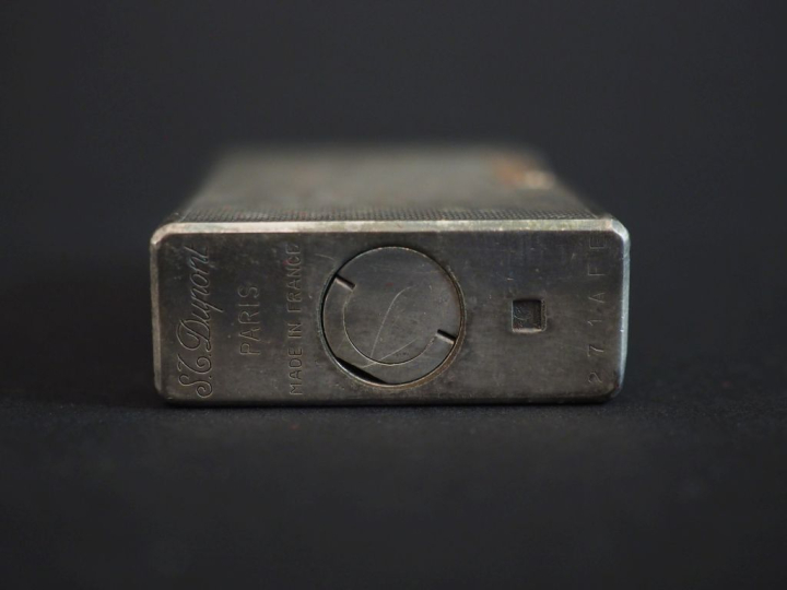 DUPONT Briquet eun métal argenté, à décor guilloché.  H. 5,8 cm Signé.