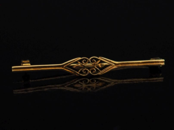 Broche barrette en or jaune 750, à décor ajouré de fleurons.  Long. 4,