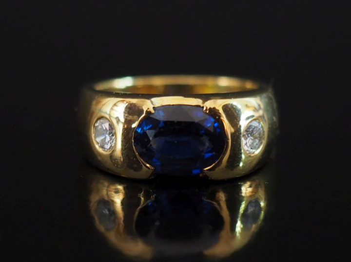 Bague bandeau en or jaune 750, sertie en son centre d'un saphir épaulé