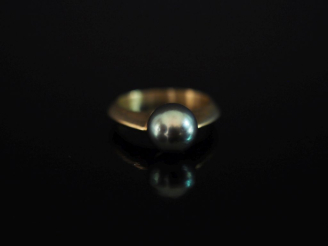 Vente aux enchères Bague en or jaune 750, sertie en son centre d'une perle grise.  TDD. 5