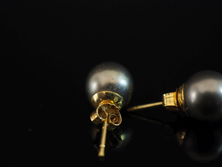 Paire de puces d'oreilles en or jaune 750, serties d'une perle grise. 