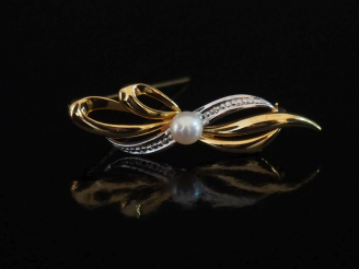 Vente aux enchères Broche barrette deux tons d'or 750 en forme de nœud, sertie en son cen