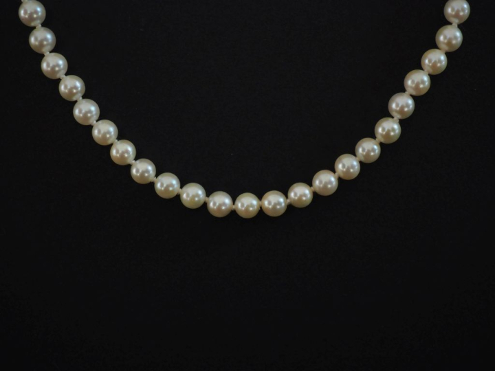 Collier de perles blanches.  Fermoir en or jaune 750. Chainette de séc