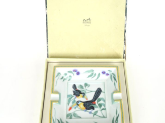 Vente aux enchères HERMES.  Cendrier en porcelaine polychrome à décor de toucans. Dim. 15