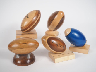 Vente aux enchères Pierre ARMENGAUD.  Cinq ballons de rugby en marqueterie et bois teinté