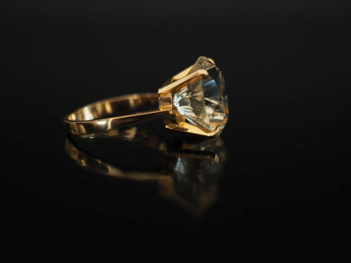 Bague en or jaune 750, sertie en son centre d'une pierre jaune pâle.  