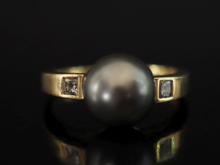 Bague en or jaune 750, sertie en son centre d'une perle grise épaulée 