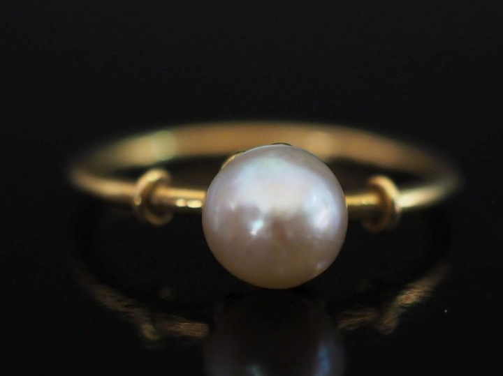 Petite bague en or jaune 750, sertie en son centre d'une perle blanche
