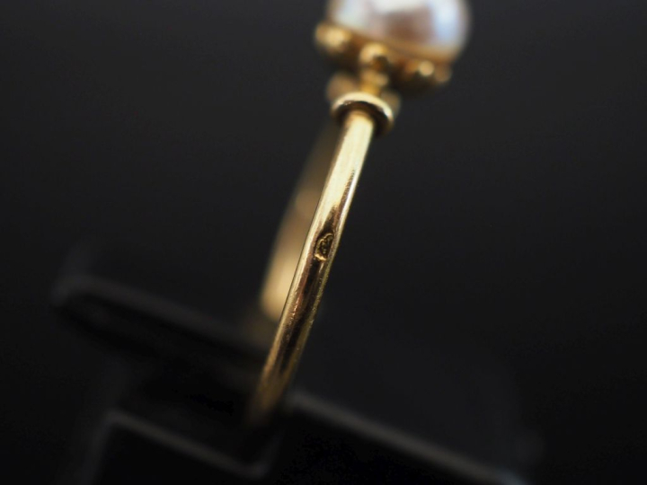 Petite bague en or jaune 750, sertie en son centre d'une perle blanche