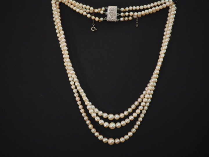Collier triple rangs de perles blanches disposées en chute.  Fermoir e