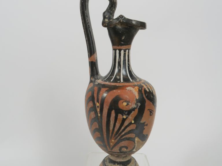 Vase grec. Œnochoé à figures rouges décorée d’une tête féminine et de 