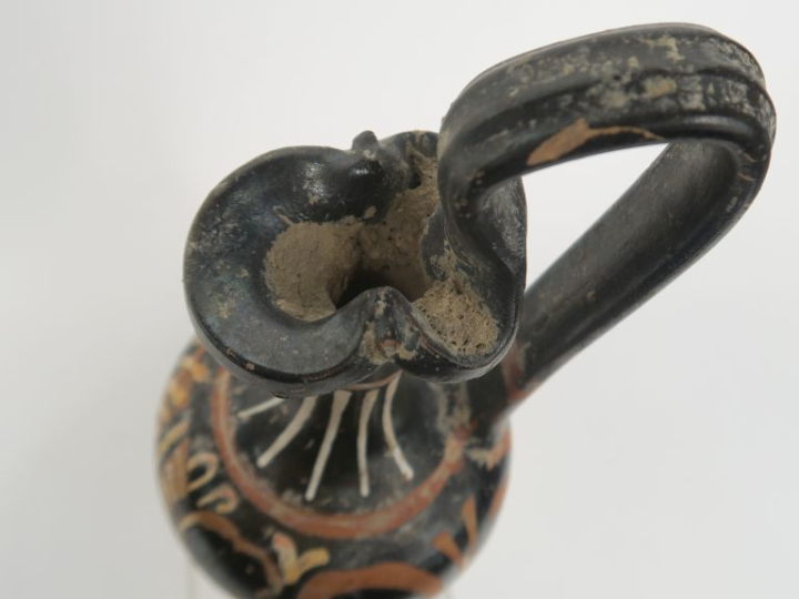 Vase grec. Œnochoé à figures rouges décorée d’une tête féminine et de 