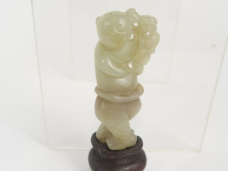 Vente aux enchères Chine. Figurine en jade d’un enfant portant une branche sur son épaule