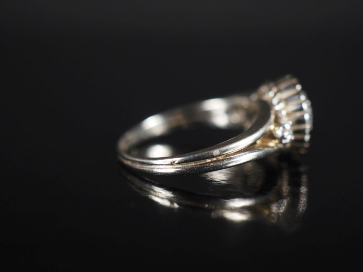 Bague marguerite en or blanc et trois diamants, le diamant central pes