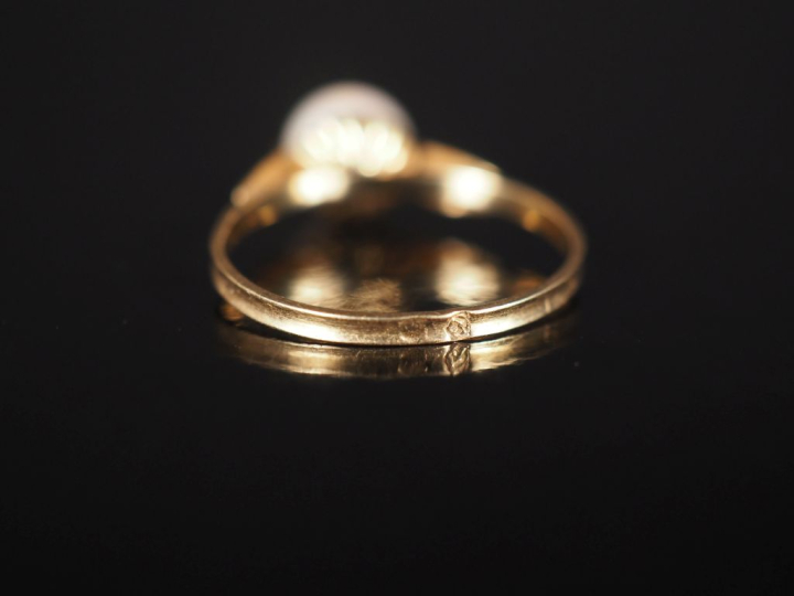 Petite bague en or jaune 750, sertie en son centre d'une perle.  TDD. 
