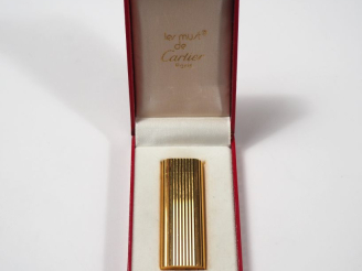 Vente aux enchères CARTIER, Must Briquet en métal doré, à décor de cannelures. Signé.  Nu