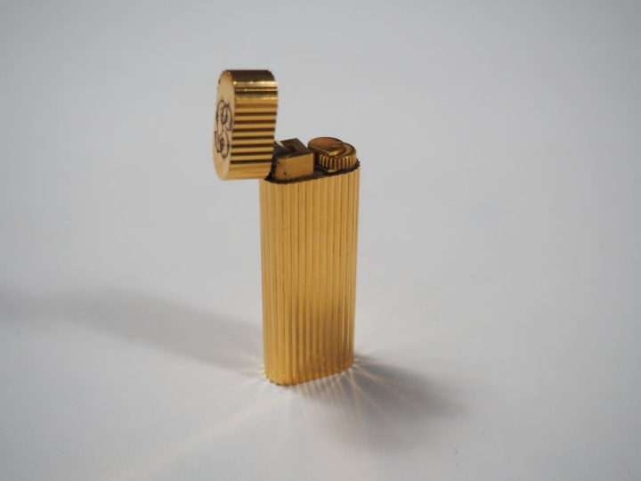 CARTIER, Must Briquet en métal doré, à décor de cannelures. Signé.  Nu