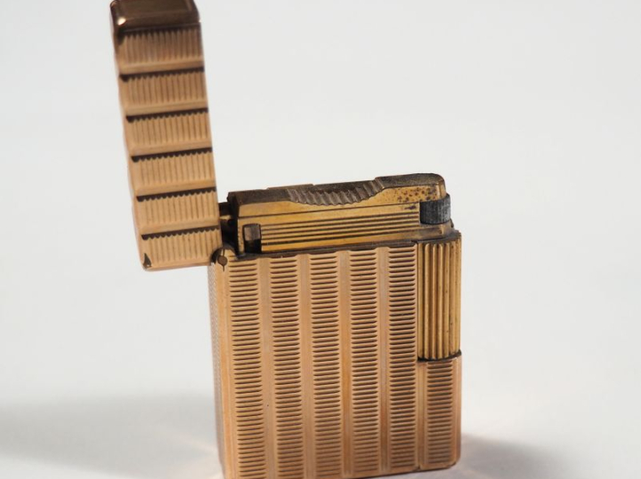 Briquet Dupont en métal doré, à décor de stries. Signé.  4,8 x 3,6 cm 