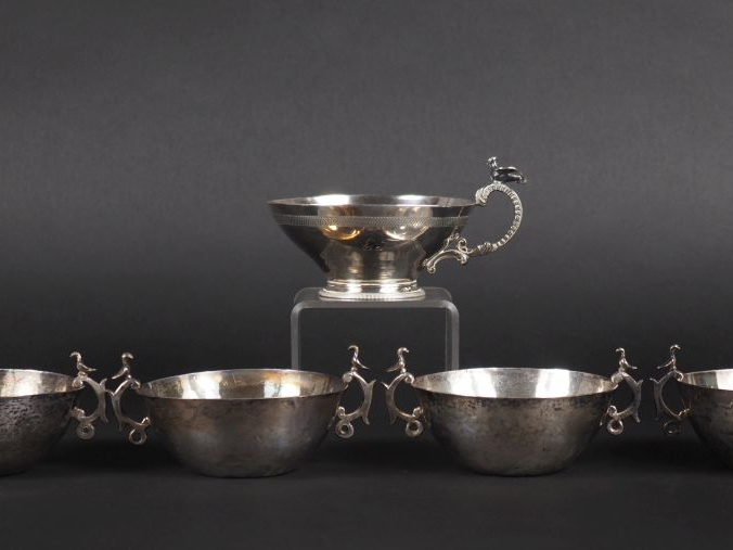 4 coupes à anses et une tasse en argent à décor d'oiseaux, et une tass