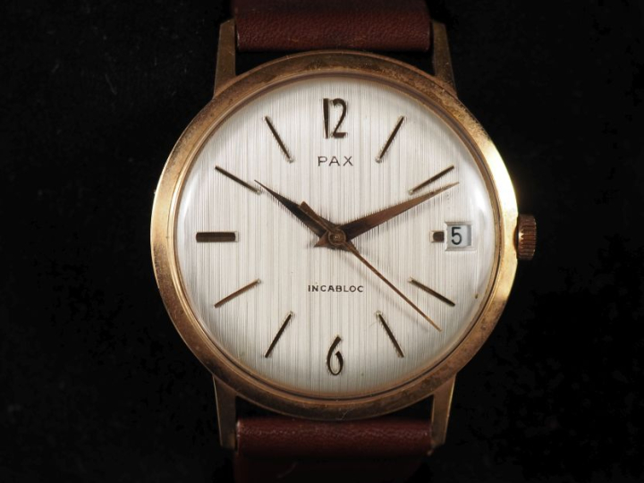 PAX Montre bracelet en métal doré.  Cadran rond à fond crème, index bâ