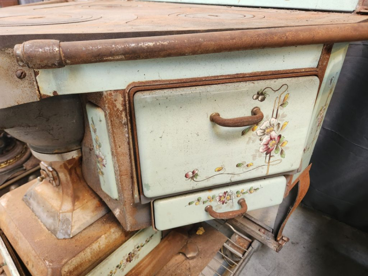 Cuisinière ancienne à décor émaillé de fleurs sur fond vert.