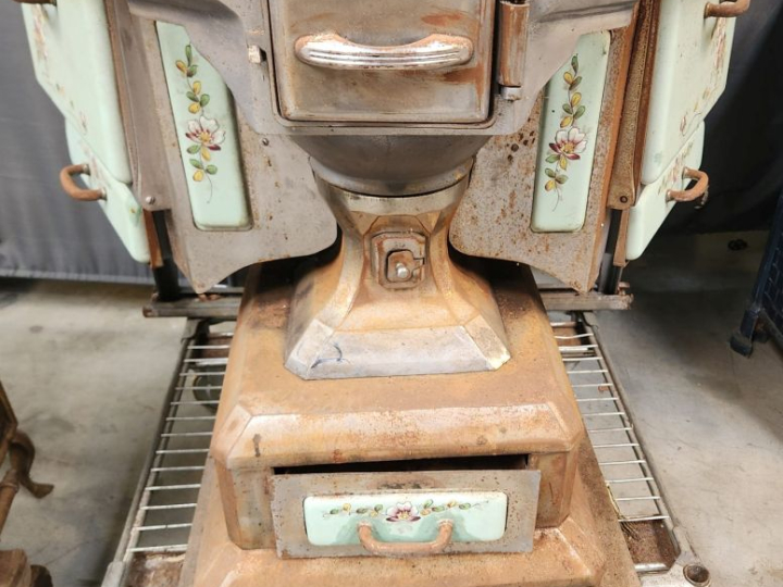Cuisinière ancienne à décor émaillé de fleurs sur fond vert.