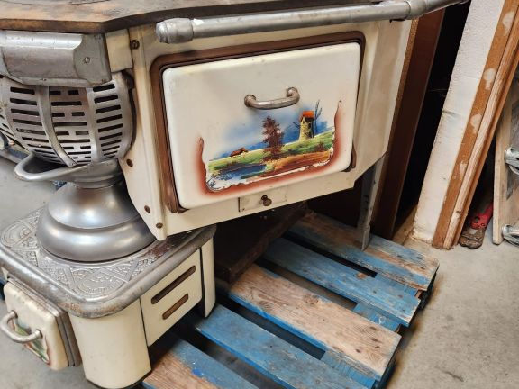 Cuisinière ancienne à décor émaillé de paysages sur fond crème.
