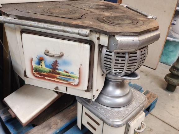 Cuisinière ancienne à décor émaillé de paysages sur fond crème.