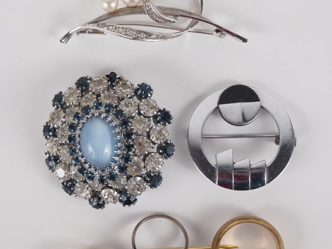 Ensemble comprenant :  - Une broche ronde en métal sertie de pierres f