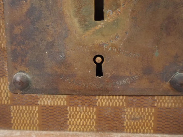 MOYNAT.  Malle de voyage en toile enduite, à décor de damier.  Poignée