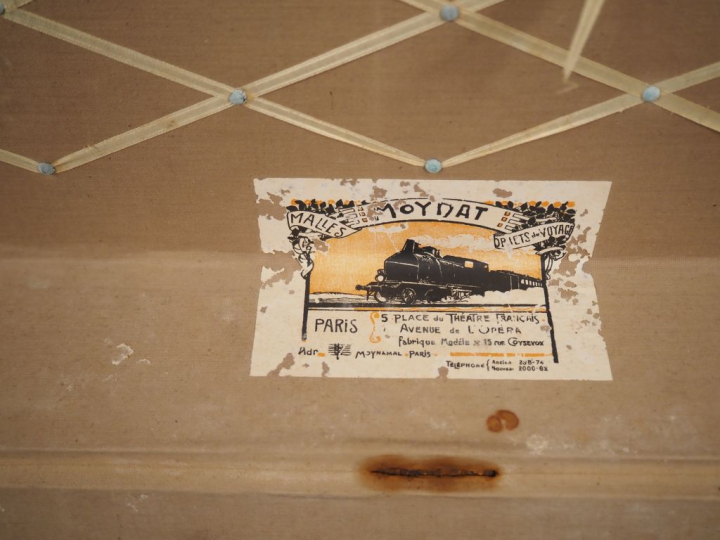 MOYNAT.  Malle de voyage en toile enduite, à décor de damier.  Poignée