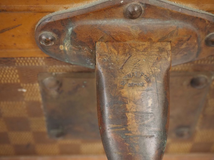 MOYNAT.  Malle de voyage en toile enduite, à décor de damier.  Poignée