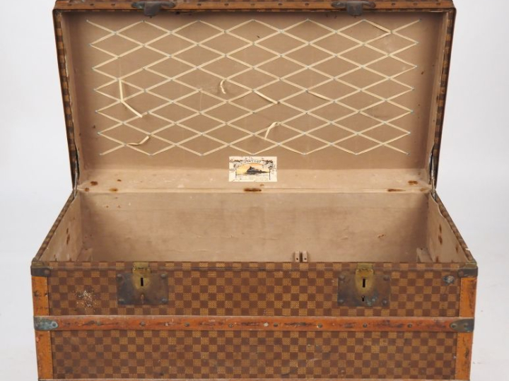MOYNAT.  Malle de voyage en toile enduite, à décor de damier.  Poignée