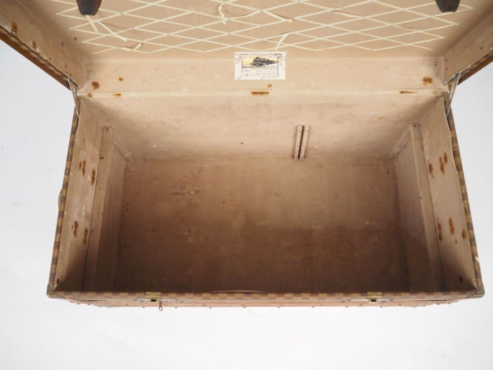 MOYNAT.  Malle de voyage en toile enduite, à décor de damier.  Poignée