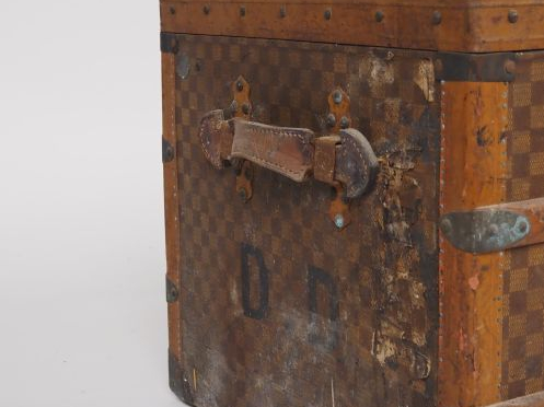 MOYNAT.  Malle de voyage en toile enduite, à décor de damier.  Poignée