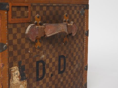 MOYNAT.  Malle de voyage en toile enduite, à décor de damier.  Poignée