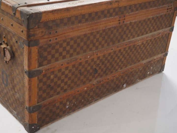 MOYNAT.  Malle de voyage en toile enduite, à décor de damier.  Poignée